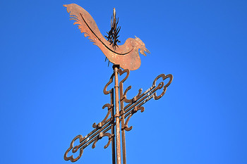 Znamenje na vrhu zvonika Špitalske cerkve na Spodnjem trgu v Škofji Loki – latinski križ s petelinom in soncem. <em>Foto: Janez Pelko</em>