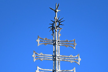 Znamenje na zvoniku baročne Kapucinske cerkve sv. Ane v Škofji Loki – križ s tremi prečkami in soncem. <em>Foto: Janez Pelko</em>