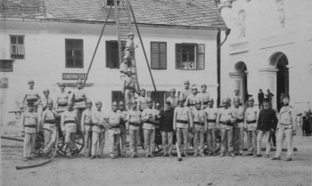 Gasilska vaja pred poslopjem šole na Trnju v Železnikih, fotografirano pred letom 1925. <em>Foto: Vengar Radovljica; hrani Muzej Železniki</em>