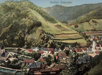 Železniki s cerkvijo sv. Antona Puščavnika (desno), razglednica, pred letom 1918, hrani Loški muzej Škofja Loka.