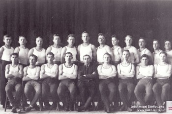 Telovadci leta 1923. Zadaj z leve: Janko Šifrer, J. Berčič, Tone Bogataj, Franc Dolenc, Jože Bernik, Lojze Hafner, Jože Celjar, Lojze Maček, Valentin Jugovic, Bernard Peter, Bine Jamnik, Nace Šmid, Janko Bernik; sedijo z leve: Jaka Čarman, Franc Mavri, Tone Rant, Franc Prevodnik, načelnik Janko Potočnik, Tone Primožič, Franc Žebre, Slavko Seliškar, Berčič Ivan. <em>Foto: Fototeka Loškega muzeja Škofja Loka</em>